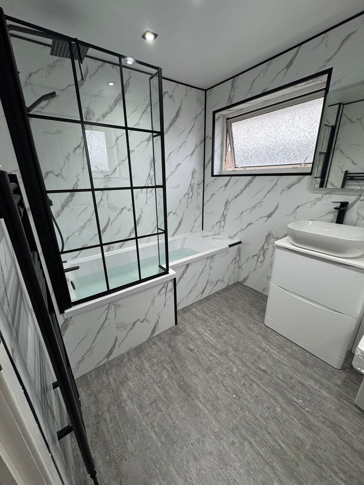 Finished ScotBath bathroom installation with modern shower and marble-effect finish